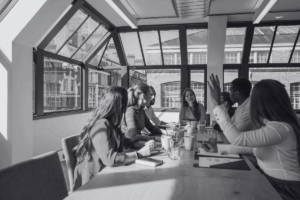 Photo noir et blanc d'une équipe dynamique autour d'une table en train de travailler sur un projet collectif
