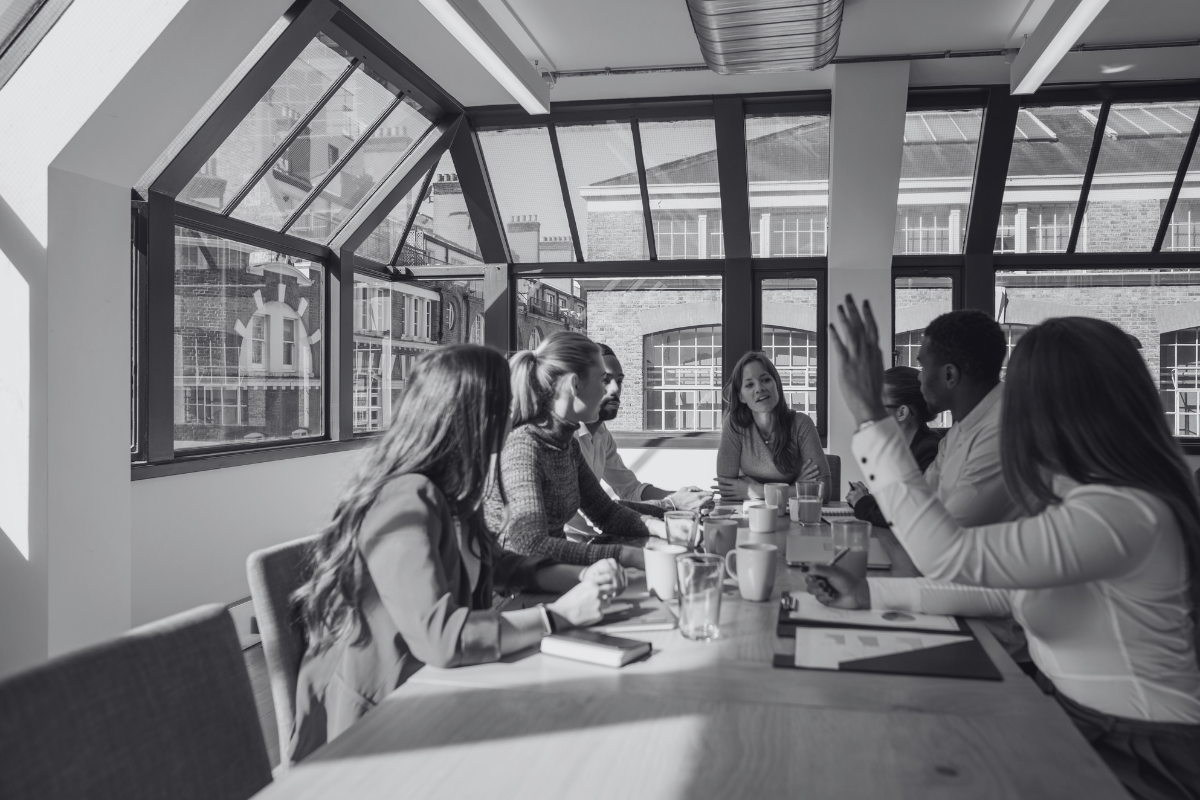 Photo noir et blanc d'une équipe dynamique autour d'une table en train de travailler sur un projet collectif