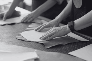 Un gros plan sur des mains travaillant du cuir, probablement dans une entreprise de maroquinerie, pour illustrer les termes marque, entreprise, image et marketing.