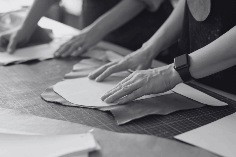 Un gros plan sur des mains travaillant du cuir, probablement dans une entreprise de maroquinerie, pour illustrer les termes marque, entreprise, image et marketing.